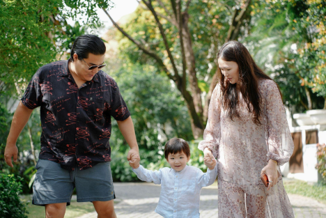 A young family walking through a pedestrian-friendly neighborhood near new Chilliwack houses, highlighting the community connection and mountain views.