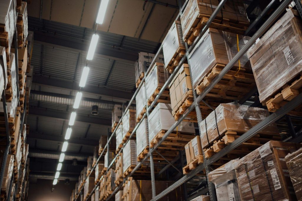 Warehouse storage facility with tall shelving holding wrapped pallets and boxes.