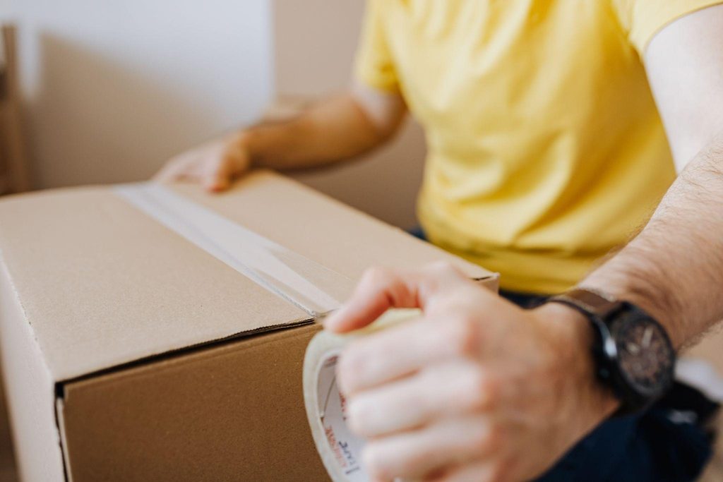 What SMBs Should Know Before Choosing a Third-Party Logistics Provider Person packing and sealing a cardboard box, part of the pack-and-ship process.
